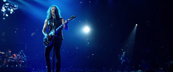 Movie still from “Metallica Through the Never” (2013), directed by Nimród Antal – A man playing a guitar on a stage; Wide shot, Low angle