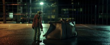 Movie still from “Metallica Through the Never” (2013), directed by Nimród Antal – A person standing next to a bag on the street; Wide shot, Low angle