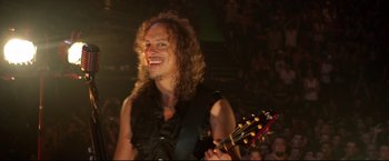 Movie still from “Metallica Through the Never” (2013), directed by Nimród Antal – A man with long curly hair is playing a guitar; Close Up shot, High angle