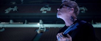 Movie still from “Metallica Through the Never” (2013), directed by Nimród Antal – A man with a tattoo on his arm looking up at the sky; Close Up shot, Low angle