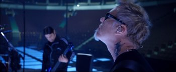 Movie still from “Metallica Through the Never” (2013), directed by Nimród Antal – A man with a tattoo is sitting in front of a guitar; Close Up shot, Low angle