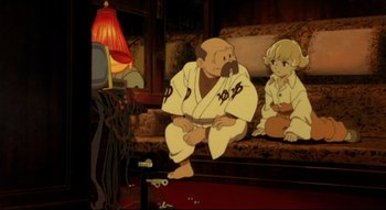 Movie still from “Metropolis” (2001), directed by Rintarô – A man and a boy in white uniforms sit in front of a television; Wide shot, High angle
