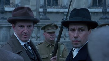 Movie still from “Michael Collins” (1996), directed by Neil Jordan – A group of men standing next to each other holding guns; Close Up shot, Low angle
