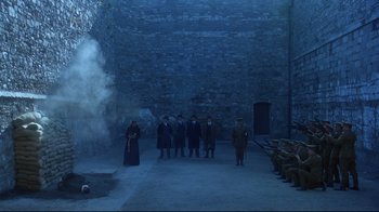 Movie still from “Michael Collins” (1996), directed by Neil Jordan – A group of people standing in a room with smoke coming out of a chimney; Extreme Wide shot, High angle