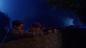 Movie still from “Michael Collins” (1996), directed by Neil Jordan – A group of people sitting on a wall at night; Medium shot, Low angle