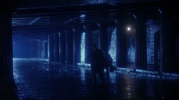 Movie still from “Michael Collins” (1996), directed by Neil Jordan – Two people are standing in the rain under a bridge; Extreme Wide shot, High angle