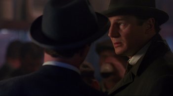Movie still from “Michael Collins” (1996), directed by Neil Jordan – A man in a suit and a hat talking to another man in a suit and a hat; Close Up shot, Over the shoulder angle