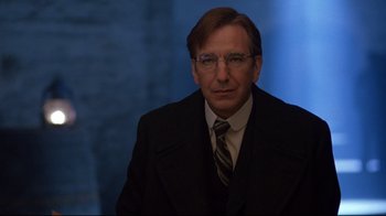 Movie still from “Michael Collins” (1996), directed by Neil Jordan – A man in a suit and tie in front of a blue wall; Close Up shot, Low angle