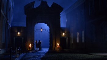 Movie still from “Michael Collins” (1996), directed by Neil Jordan – Two people are standing in front of an archway at night; Extreme Wide shot, High angle