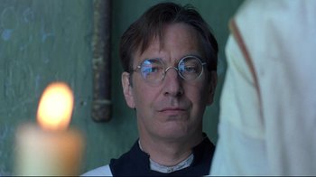Movie still from “Michael Collins” (1996), directed by Neil Jordan – A man wearing glasses and a priest's collar; Close Up shot, Over the shoulder angle