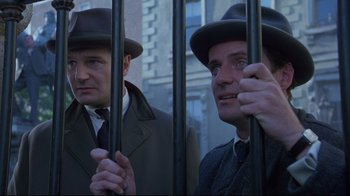 Movie still from “Michael Collins” (1996), directed by Neil Jordan – A couple of men standing next to each other holding bars; Medium shot, Low angle