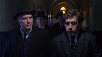 Movie still from “Michael Collins” (1996), directed by Neil Jordan – A group of men standing next to each other in suits; Medium shot, Low angle