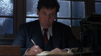 Movie still from “Michael Collins” (1996), directed by Neil Jordan – A man sitting at a table writing on a piece of paper; Close Up shot, Low angle