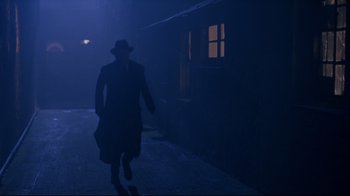 Movie still from “Michael Collins” (1996), directed by Neil Jordan – A man walking down a street in a dark place; Wide shot, Low angle
