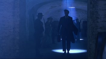 Movie still from “Michael Collins” (1996), directed by Neil Jordan – A group of people in a dark room with lights; Wide shot, Low angle