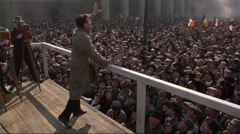 Movie still from “Michael Collins” (1996), directed by Neil Jordan – A crowd of people are gathered around a man; Wide shot, High angle