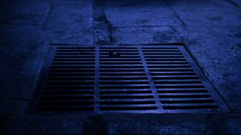 Movie still from “Michael Collins” (1996), directed by Neil Jordan – A metal grate on the ground in the dark; Wide shot, Overhead angle