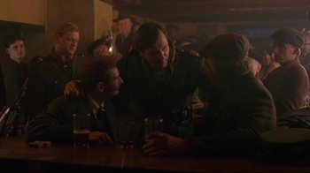 Movie still from “Michael Collins” (1996), directed by Neil Jordan – A group of men sitting at a table in a bar; Medium shot, Over the shoulder angle