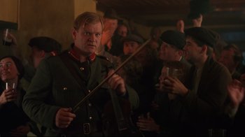 Movie still from “Michael Collins” (1996), directed by Neil Jordan – A group of people in a room with a man in uniform holding a sword; Medium shot, Low angle