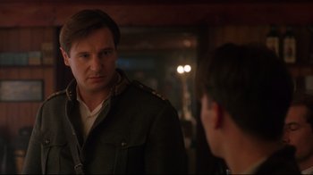 Movie still from “Michael Collins” (1996), directed by Neil Jordan – A man wearing a military style jacket talking to another man in front of a mirror; Close Up shot, Over the shoulder angle