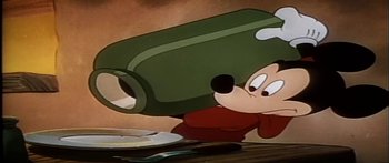 Movie still from “Mickey and the Beanstalk” (1947), directed by Hamilton Luske – A cartoon of mickey mouse holding a large object in front of his face; Medium shot, Low angle