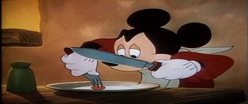 Movie still from “Mickey and the Beanstalk” (1947), directed by Hamilton Luske – A mickey mouse holding a knife and fork over a white plate; Medium shot, Low angle