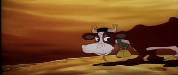 Movie still from “Mickey and the Beanstalk” (1947), directed by Hamilton Luske – A cartoon of a cow standing on top of a dirt hill; Wide shot, High angle