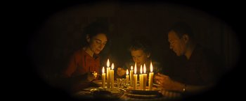 Movie still from “Micmacs” (2009), directed by Jean-Pierre Jeunet – A group of people sitting around a table with candles; Medium shot, High angle