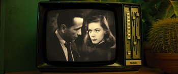 Movie still from “Micmacs” (2009), directed by Jean-Pierre Jeunet – A black and white photo of a man and a woman on a television screen; Extreme Close Up shot, Over the shoulder angle