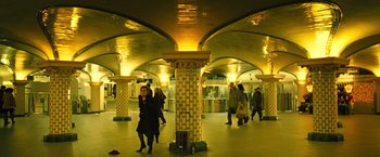 Movie still from “Micmacs” (2009), directed by Jean-Pierre Jeunet – People are walking in a train station while a woman talks on her phone; Extreme Wide shot, High angle