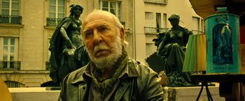 Movie still from “Micmacs” (2009), directed by Jean-Pierre Jeunet – An old man with a beard and a leather jacket; Medium shot, Low angle