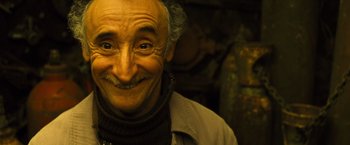 Movie still from “Micmacs” (2009), directed by Jean-Pierre Jeunet – An old man with a beard and mustache smiling for the camera; Close Up shot, Low angle