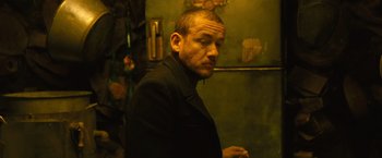 Movie still from “Micmacs” (2009), directed by Jean-Pierre Jeunet – A man in a black jacket standing next to a wall; Close Up shot, Low angle