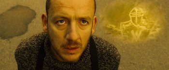 Movie still from “Micmacs” (2009), directed by Jean-Pierre Jeunet – A person wearing a sweater and looking at the camera; Close Up shot, Low angle