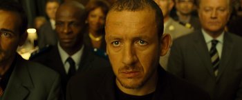 Movie still from “Micmacs” (2009), directed by Jean-Pierre Jeunet – A person wearing a suit and tie; Close Up shot, Low angle