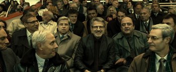 Movie still from “Micmacs” (2009), directed by Jean-Pierre Jeunet – A group of people sitting in a room; Medium shot, High angle