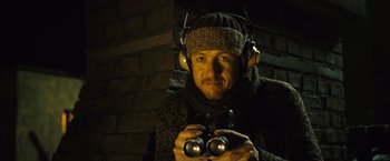 Movie still from “Micmacs” (2009), directed by Jean-Pierre Jeunet – A man wearing headphones and holding a pair of binoculars; Close Up shot, Low angle