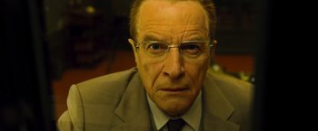 Movie still from “Micmacs” (2009), directed by Jean-Pierre Jeunet – An older man wearing a suit and glasses; Close Up shot, Low angle