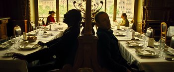 Movie still from “Micmacs” (2009), directed by Jean-Pierre Jeunet – Two men sitting at a table in a restaurant; Medium shot, Low angle