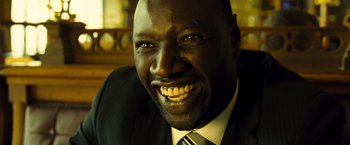 Movie still from “Micmacs” (2009), directed by Jean-Pierre Jeunet – A person wearing a suit and tie; Close Up shot, Low angle