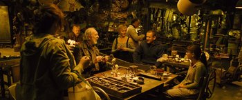 Movie still from “Micmacs” (2009), directed by Jean-Pierre Jeunet – A group of people sitting at a table in a room; Medium shot, High angle