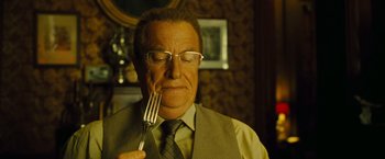Movie still from “Micmacs” (2009), directed by Jean-Pierre Jeunet – An older man holding a fork in his mouth; Close Up shot, Over the shoulder angle