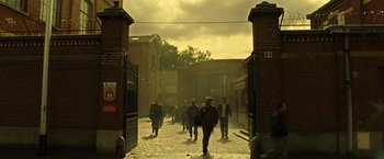 Movie still from “Micmacs” (2009), directed by Jean-Pierre Jeunet – A group of people walking down a brick street; Extreme Wide shot, High angle