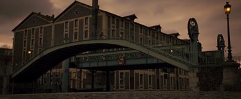 Movie still from “Micmacs” (2009), directed by Jean-Pierre Jeunet – A building that has a bridge going over it; Extreme Wide shot, Low angle