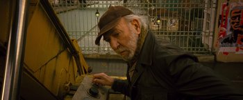 Movie still from “Micmacs” (2009), directed by Jean-Pierre Jeunet – An older man in a brown hat and a brown jacket; Close Up shot, High angle