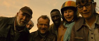 Movie still from “Micmacs” (2009), directed by Jean-Pierre Jeunet – A group of people standing next to each other smiling; Close Up shot, High angle