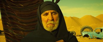 Movie still from “Micmacs” (2009), directed by Jean-Pierre Jeunet – An old man with a beard wearing a black headscarf; Close Up shot, Low angle