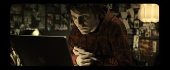 Movie still from “Micmacs” (2009), directed by Jean-Pierre Jeunet – A young man is looking at a computer screen; Close Up shot, High angle