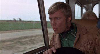 Movie still from “Midnight Cowboy” (1969), directed by John Schlesinger – A man sitting in the driver's seat of a car; Close Up shot, Over the shoulder angle