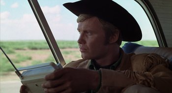 Movie still from “Midnight Cowboy” (1969), directed by John Schlesinger – A man wearing a cowboy hat while sitting in a car; Close Up shot, Low angle
